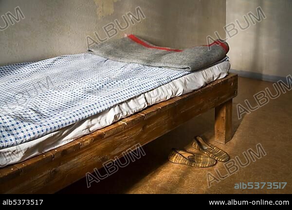 Cot with original bed covers, blanket and slippers, Berlin-Hohenschoenhausen memorial, former prison of the GDR's secret service, Berlin, Germany, Europe.