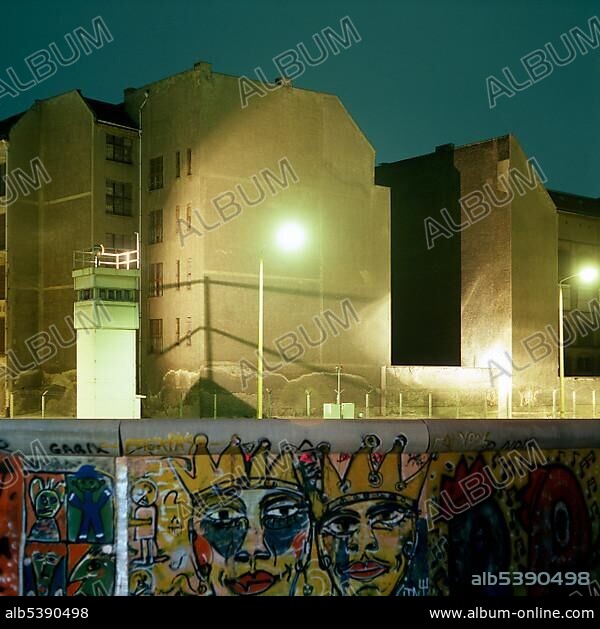 Berlin Wall with graffiti, guard tower and illuminated no man's land in the back, Berlin, Germany, Europe.