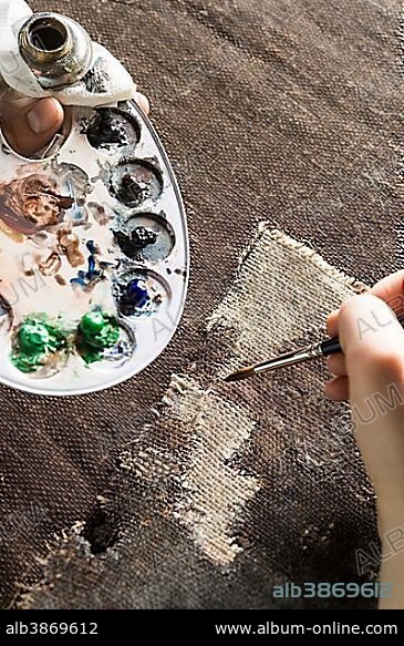 Restoration studio, restorer, hand patinates the woven in patch of linen with brush and paint, Munich, Bavaria, Germany, Europe.