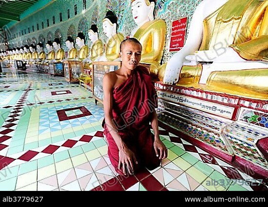 A monk kneeling in front of Buddha statues in a monastery, Umin Thounzeh Pagoda, Sagaing, Mandalay, Burma also known as Myanmar, Southeast Asia, Asia.