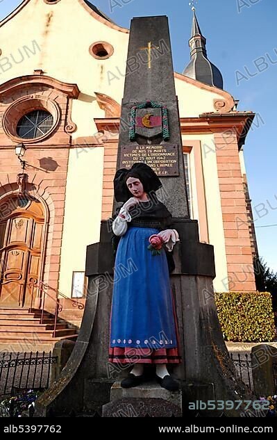 Second World War memorial with statue of woman wearing traditional Alsatian costume in front of a church, Ingersheim, Alsace, France, Europe.