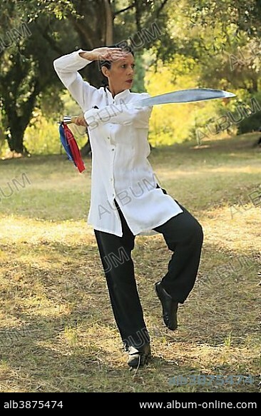 Tai Chi with a sword, demonstration in an olive grove, Régine Zanini, two-time silver medalist at the Tai Chi Championships 2012, Menton, French Riviera, Alpes-Maritimes, Provence-Alpes-Côte d’Azur, France, Europe.