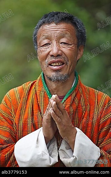 Man, 58 years, in Gho-dress with hands clasped, portrait, Jakar, Bumthang Valley, Bhutan, Asia.