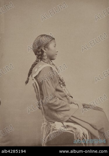 Mik-Tekhe, from the Omaha Tribe.. She's 13 and is the first wife of Hard Chief.. Photograph in: "Collection anthropologique du prince Roland Bonaparte : Peaux-rouges" ('Anthropological collection of Roland Bonaparte, Prince of Canino and Musignano: Red Indians'). Photograph taken in the Jardin d'Acclimatation in Paris. . The 19 Red Indians that were exhibited at the Jardin d'Acclimatation in November 1883 were part of the Omaha tribe. They were 1121 when Roland Bonaparte photographied them. The members of the tribe used to live in the United-States and their territory was located on the East side of the Missouri (Nebraska), between Sioux-City and Omaha.