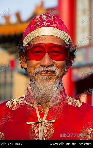 Portrait, old chinese man with red glasses, hat and beard, Chinese New Year, Spring Festival, Chinatown, Bangkok, Thailand, Asia.