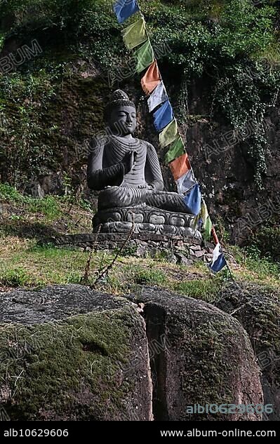 Buddha statue and Tibetan prayer flags in front of the entrance to the Messner Mountain Museum near Bolzano, Italy, Europe.