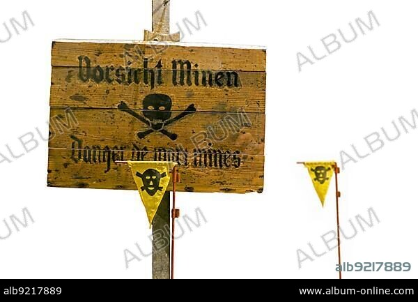German World War Two wooden Vorsicht Minen, Caution Land Mines warning sign and marker flags marking minefield, mine field against white background.