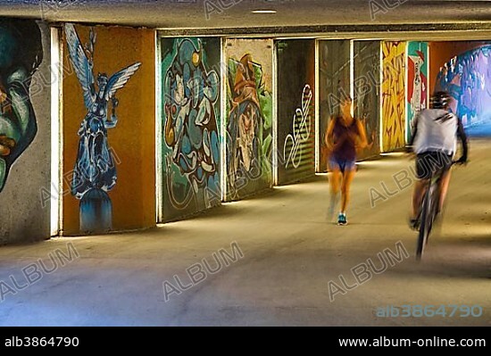 Pedestrian underpass with graffiti art, with a cyclist and a jogger, Maximilian Park, Munich, Upper Bavaria, Bavaria, Germany, Europe.
