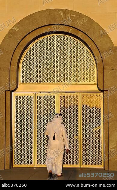 Qatari wearing traditional dress with gutra, gold-plated west entrance, Museum of Islamic Art, designed by I.M. PEI, evening atmosphere, Corniche, Doha, Qatar, Persian Gulf, Middle East, Asia.