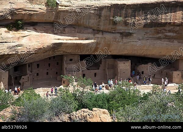 Visitors tour the Spruce Tree House cliff dwelling at Mesa Verde National Park, featuring cliff dwellings of ancestral Puebloans that are nearly a thousand years old, Cortez, Colorado, USA, North America.