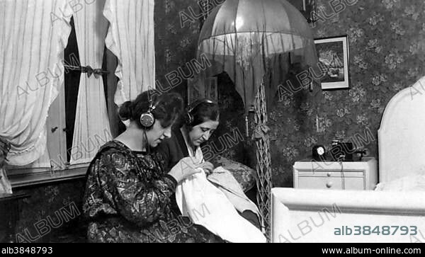 Two women listening to radio with headphones, stitching, 1930s, Germany, Europe.