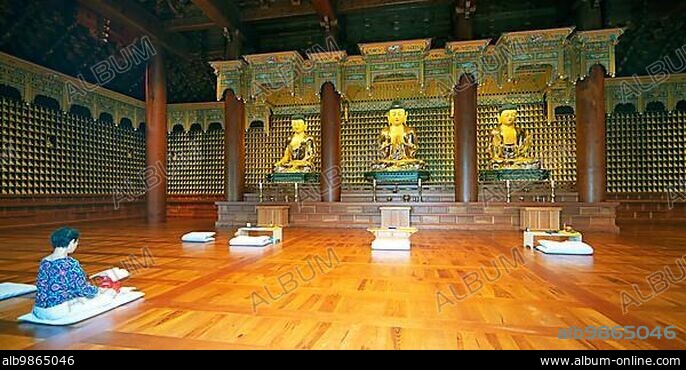 Korean woman praying at the golden Buddha statues in the temple, May 18th Memorial Park, Gwangju, Jeollanam-do Province, South Korea, Asia.