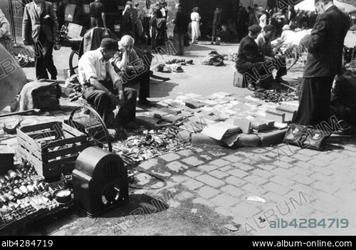 Impromptu flea market in the ruins of. Stettin (now Szczecin), in Polish Pomerania, late 1945. . Everything was lacking in Poland, which had been devastated by the German and Soviet armies during the 2nd World War. . The overwhelmed faces of the inhabitants seen in this photo tell volumes about the profound destitution to which they were subjected.