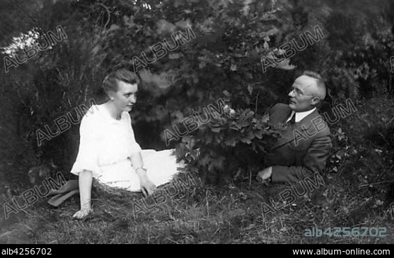 Couples, man and woman lie in a meadow hiding legs behind a bush, 1930s, Germany, Europe.
