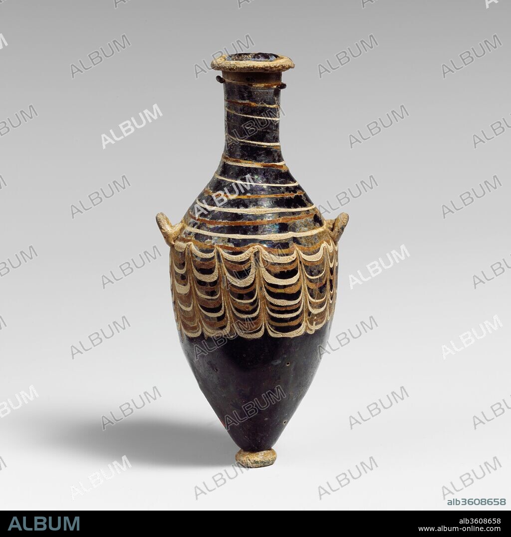 Glass unguentarium (perfume bottle). Culture: Greek, Eastern Mediterranean, possibly Alexandrian. Dimensions: H.: 4 in. (10.1 cm). Date: 3rd century B.C..
Translucent light blue, with opaque turquoise green handles, rim-disk, and pad-base; trails in opaque white and uncertain color, appearing opaque reddish brown. 
Turquoise green trail applied as outsplayed rim-disk around jagged top edge of neck; tall, slender neck, tapering slightly downward; steeply sloping shoulder; elongated piriform body, tapering downward to applied; small pad-base with uneven flat bottom; two small loop handles applied to edge of shoulder and top of body with everted upward angle.
White and reddish brown trails attached at top of neck and wound down as alternate spiral lines, tooled into a festoon pattern round upper half of body, with fifteen upward tooling strokes.
Intact; some dulling and pitting, especially of turquoise blue additions, and areas of creamy brown weathering and iridescence.