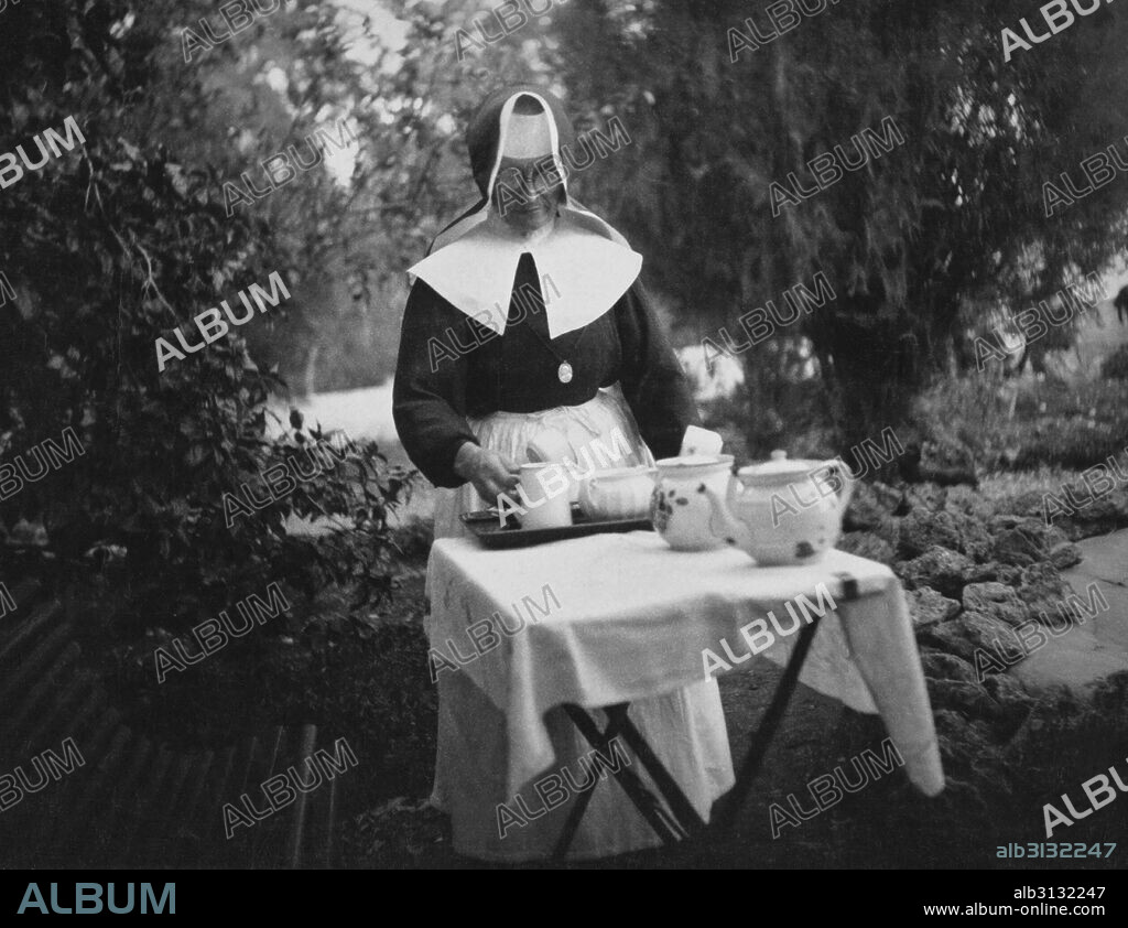 Haifa, Palestine:  c. 1930 A German Catholic nun at the German Hospice preparing out a tea setting outdoors.