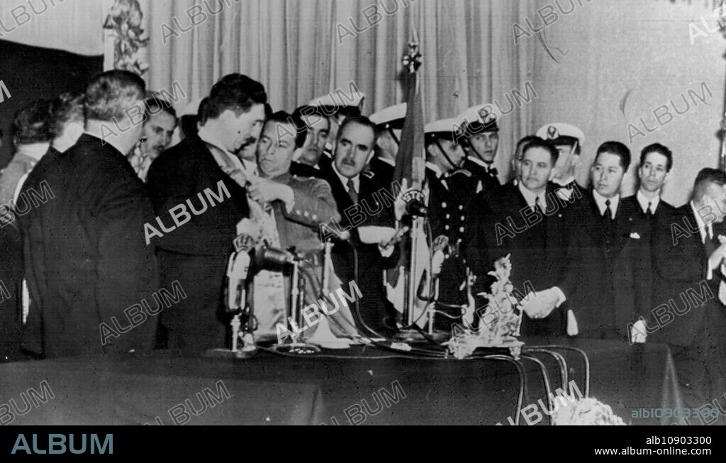 Aleman Receives Presidential Sash -- President Miguel Aleman of Mexico, (second from left) has the sash denoting the office of President of Mexico pinned on by Capt. Alfonso Castillo, private secretary of out-going president, Avila Camacho (left) after receiving the sash from Camacho. House committee members together with honor guard from Mexican Army and Navy look on. December 01, 1946. (Photo by AP Wirephoto).