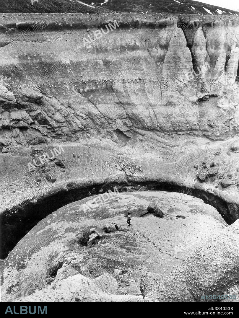Cliffs of volcanic ash and pumice tower over a geologist exploring Deep Creek canyon during the summer of 1965. Volcanic deposits were laid down during eruption of Mt. Katmai in 1912. Katmai National Monument contains 2,697,590 acres and was established in 1918. The area features several of Alaska's active volcanoes, including Mount Triton, and the famed Valley of 10,000 Smokes.