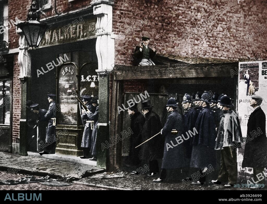 The Sidney Street siege, Whitechapel, London, 1911, (1935). Winston Churchill, then Home Secretary, the left of the top-hatted figures, is earnestly watching the activities of the soldiers of the Scots Guards and the police. The Sidney Street siege occurred after a gang of heavily armed Latvian burglars shot five police officers who attempted to arrest them as they attempted to break into a jeweller's shop. Four of the policemen died. Three members of the gang were cornered at 100 Sidney Street and surrounded by the police. A gunfight ensued, but the police had inferior weapons and reinforcements in the form of soldiers from the Scots Guards were called in by order of Churchill, who arrived to observe the scene himself. After six hours of fighting, the building caught fire and Churchill controversially gave the order that the Fire Brigade take no action. Two of the burglars' bodies were discovered in the burned out building but no trace of the third was ever found. A print from King Emperor's Jubilee, 1910-1935, by FGH Salusbury, Daily Express Publications, London, 1935. (Colorised black and white print).