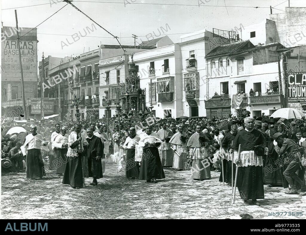 Sevilla, mayo de 1919. Custodia 2.- Procesión del Corpus Christi. En la imagen, la custodia de Arfe por la calle Fernández y González. A la izquierda de la foto, el solar donde se está construyendo el edificio de «La Adriática» (1914-22), de José Espiau y Muñoz. Juncia y romero en el recorrido, sombrillas para el sol y soldados rindiendo honores al Santísimo Sacramento.