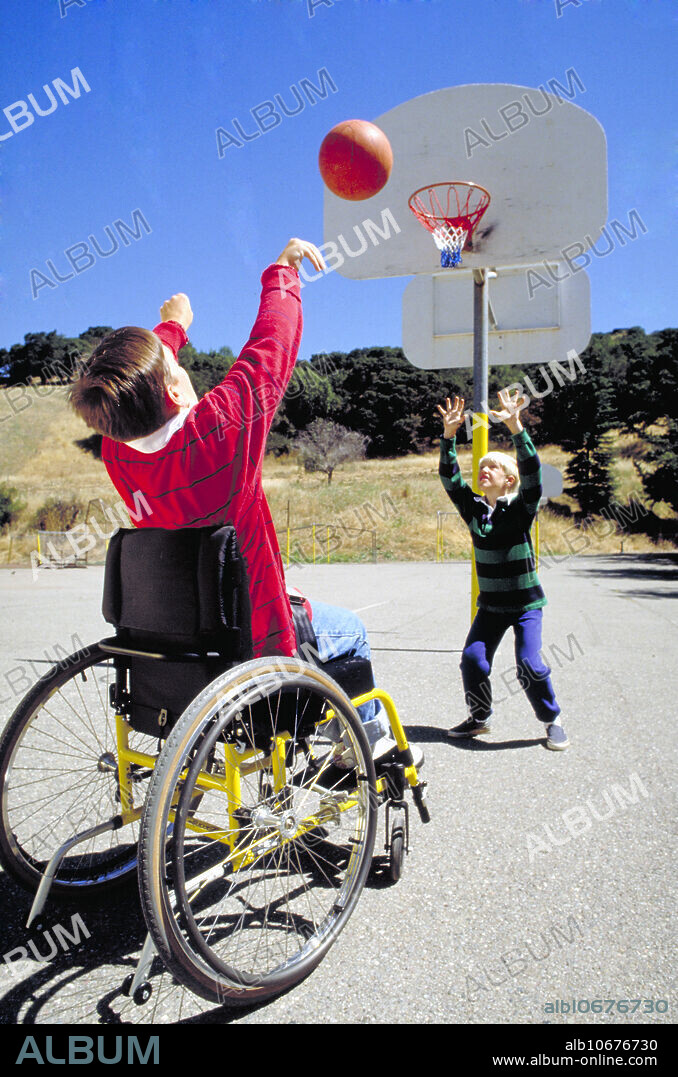 Disabled boy in wheelchair shoots hoops