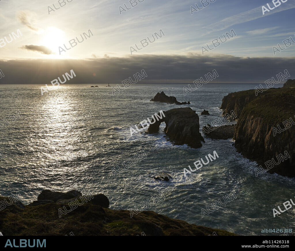 Sunset at Land's End over Enys Dodman rock arch, Longships Lighthouse, Cornwall, England, United Kingdom, Europe.