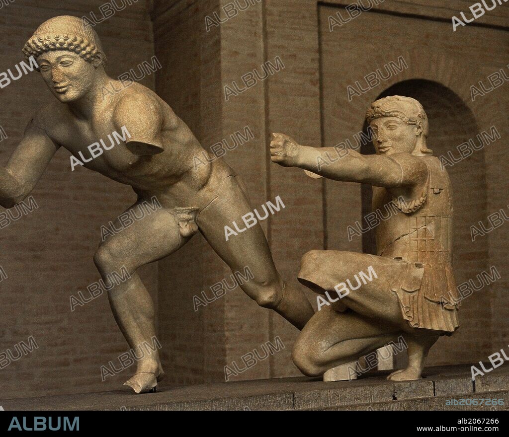 ARTE GRIEGO. GRECIA. Grupo escultórico del Frontón Este del templo de Egina. Alrededor de 480 aC. Dos figuras que representan guerreros (griegos) en la Guerra de Troya. El ayudante del guerrero, y el arquero arrodillado, con piel de león, como Heracles / Hercules. Glyptothek. Munich. Alemania. Europa.