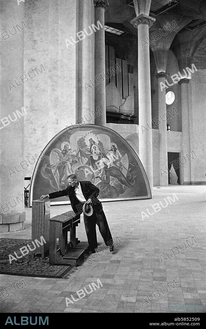 ERICH LESSING. A man drops a contribution into the collection box of a new church in Katowice (Stalingorod, for a few years), a mining town in Upper Silesia. The church was financed by subsidies and private donations. Katovice, Poland,1956.