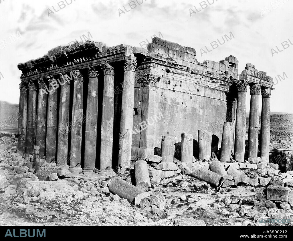 The Temple of Bacchus is one of the best preserved and grandest Roman temple ruins in the world. The temple was commissioned by Roman Emperor Antoninus Pius and built close to the courtyard in front of the larger temple of Jupiter-Baal. The period of construction is generally considered between 150 AD to 250 AD. The temple is is 216 feet long, 115 wide, and 102 feet high. Its walls are adorned by 42 un-fluted Corinthian columns, 19 of which remain upright in position standing 62 feet high. The columns support a richly carved entablature. Inside, the cella is decorated with Corinthian half-columns flanking two levels of niches on each side, containing scenes from the birth and life of Bacchus. Baalbek is a town in the Beqaa Valley of Lebanon situated east of the Litani River. After Alexander the Great conquered the Near East in 334 BC, the existing settlement was named Heliopolis. The city retained its religious function during Greco-Roman times, when the sanctuary of the Heliopolitan Jupiter-Baal was a pilgrimage site, and one of the largest sanctuaries in the empire. Starting in the last quarter of the 1st century BC (reign of Augustus) and over a period of two centuries (reign of Philip the Arab), the Romans had built a temple complex in Baalbek consisting of three temples: Jupiter, Bacchus and Venus. On a nearby hill, they built a fourth temple dedicated to Mercury. Photographed by Peter Bergheim, circa 1860-80.