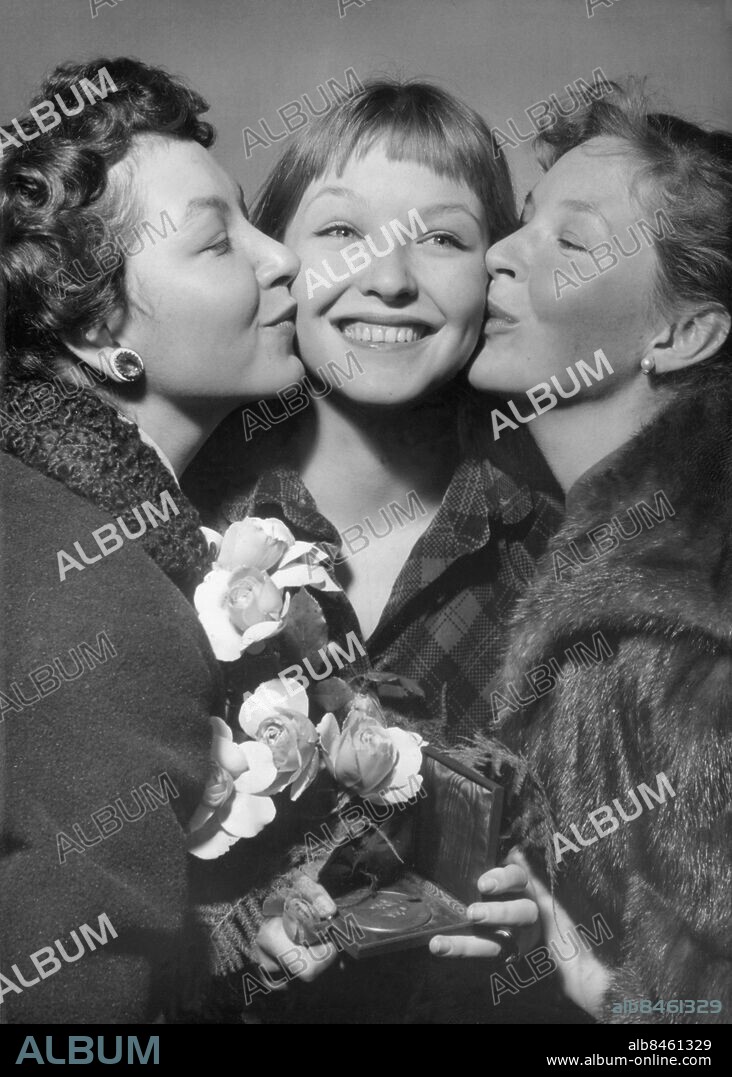 Orig. bildtext... A MARINA VLADY LE PRIX SUZANNE BIANCHETTI. C'est à la jeune artiste Marina Vlady, âgée de 17 ans, la plus jeune soeur d'Odile Versois qui a tourné déjà de nombreux films en Italie, un film en Allemagne et Avant le Déluge d'André Cayatte en France, qu'a été décerné aujourd'hui par les Auteurs de Films, le Prix Suzanne Bianchetti, destiné à récompenser une jeune artiste qui s'est révélée dans l'année. La jeune Marina Vlady, toute souriante, tenant la médaille qui vient de lui ètre décernée dans la main, est embrassée par ses deux soeurs: Odile Versois (à droite) et Hélène Vallier (à gauche). Anm. Prix Suzanne Bianchetti är ett pris inom fransk film som sedan 1937 årligen tilldelas den mest lovande unga kvinnliga skådespelerskan. M Vlady, eg. de Poliakoff-Baidaroff, f. 1938, fransk skådespelerska, syster till Odile Versois och Hélène Vallier. O Versois, 1930-1980, fransk skådespelerska, syster till Marina Vlady och Hélène Vallier. H Vallier, 1932-1988, fransk skådespelerska, syster till Marina Vlady och Odile Versois. Se även BBT678 Bildserier Fotoreportage Syskon Systrar Pussar på kinden Leende Rosor Etuier Örhängen Gratulationer Blundar Trio Mönster CD523 persons: MARINA VLADY;HÉLÈNE VALLIER;ODILE VERSOIS sites: FRANKRIKE.