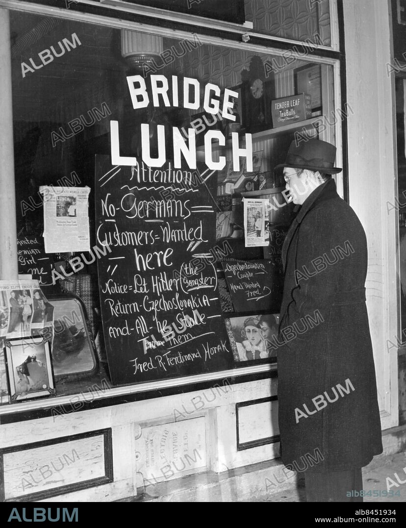 Orig. bildtext... RESTAURANT OWNER BARS GERMANS Somerville, Mass. A spectator reading the sign in the window of Fred R. Ferdinand Horak's cafe here, which expresses his views on the recent dissolution of Czecho-Slovakia by Adolf Hitler - no german patriots wanted in the establishment. Anm. Omvänd rasism Skyltar CD203 sites: TJECKOSLOVAKIEN* ;TYSKLAND* ;USA.