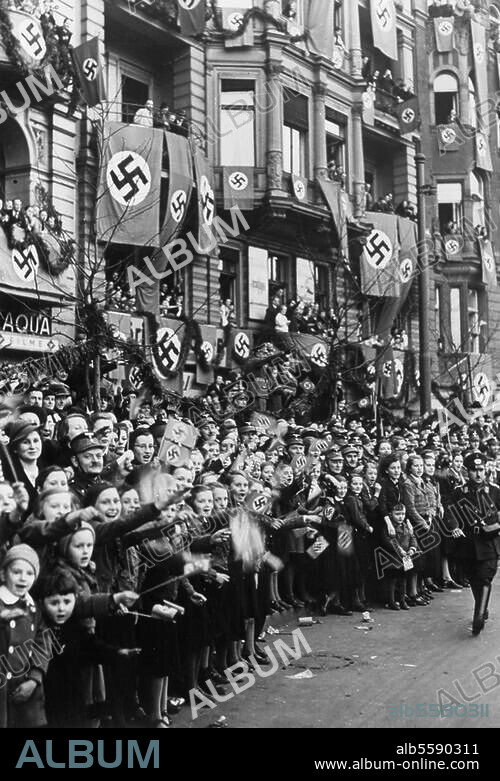Berlin, 16 March 1938. Hitler's 'Journey of Triumph' through Berlin - Hitler returns after the. 'Anschluss' with Austria on 12/3/1938. On-lookers waving flags on the street into which Hitler will travel. Photo.