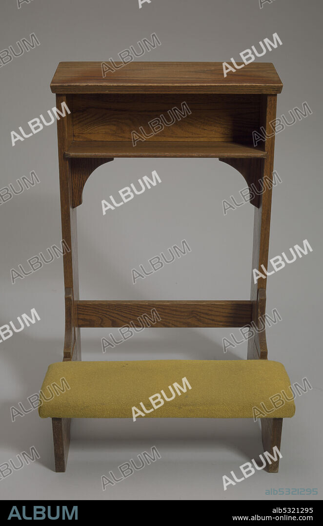 A wood kneeling altar with a yellow-green padded knee rest. The altar has small cubbyhole under the top shelf. The shelf is slightly tilted down toward the knee pads. The bottom of the shelf and cubbyhole are supported by two curved arches on either side, attached to the side planks. On either side of the altar at the top of the side planks is a carved cross. A small rectangular support board is near the base of the altar and connects the two side planks. Kneepads are attached to the fixed base with two solid horizontal planks on either side. A small, wood, inverted arch support connects the knee rest to the vertical side planks.