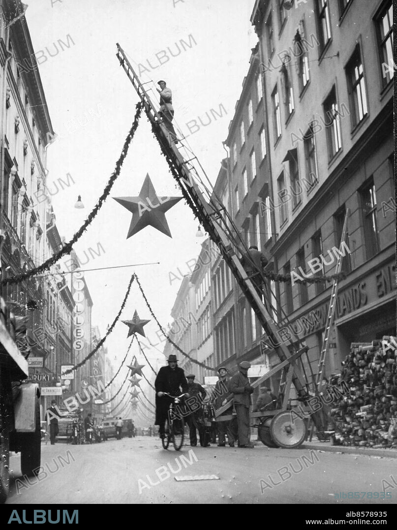 Stockholm 1945-11-28. Juldekorationer på Regeringsgatan. Redan i skarven till julmånaden börjar Stockholm rusta för doppardagsstämningen. Tidigt på tisdagsmorgonen var man i farten med pyntet på Regeringsgatan och den förbiilande fotografen passade förstås på att få en vy av förberedelserna. Rimfrosten behagade inställa upptiningsverksamheten för att ge den rätta lystern åt bilden.. Foto: Expressen / TT / Kod: 192. ** AFTONBLADET OUT **.