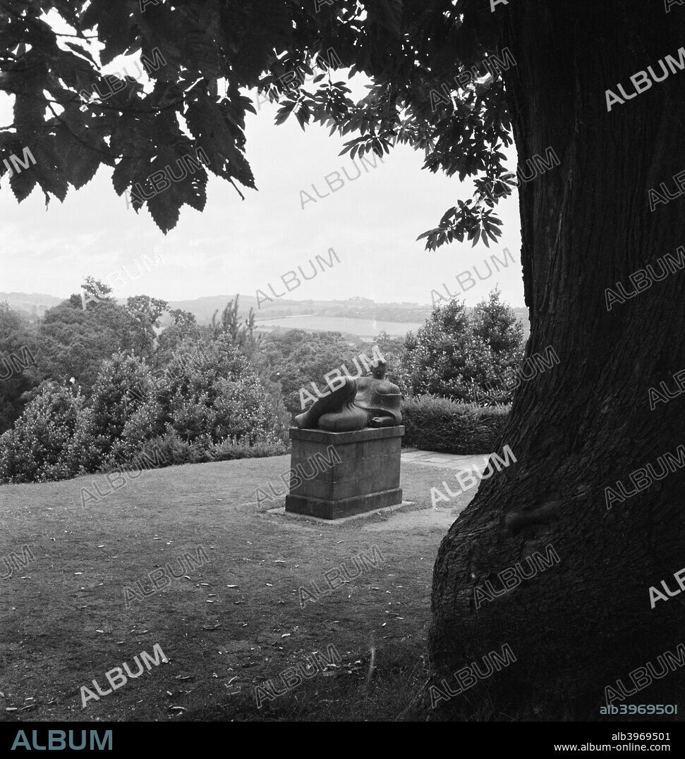 Christopher Martin Memorial, Dartington Hall, Devon, 1955-1965. View past the trunk of a Spanish Chestnut tree towards the Christopher Martin memorial, sculpted by his friend Henry Moore in 1945-46 and situated in the gardens of Dartington Hall in Devon, where Martin was the first administrator of the arts.