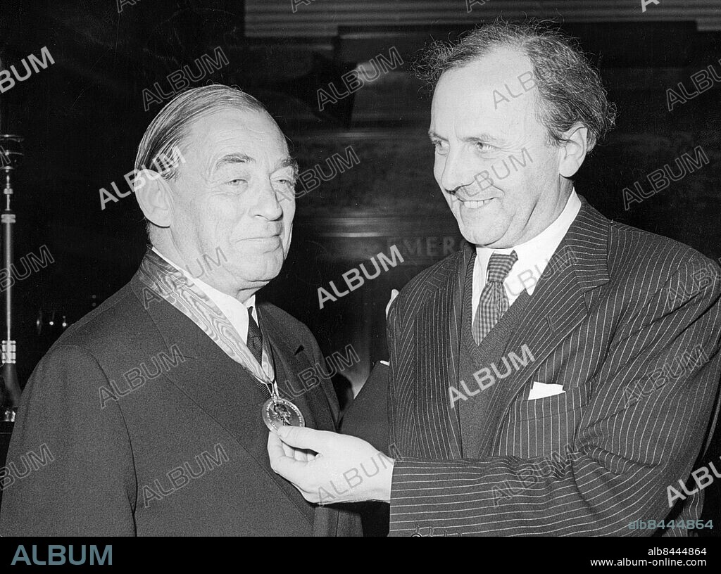 Orig. bildtext... FINNISH ARCHITECT HONOURED IN LONDON. Mr. Alvar Aalto, the famous Finnish architect, was presented with the Royal Gold Medal for Architecture at the Royal Institute of British Architects in London. This is the first time that a Finnish citizen has received this high award. PHOTO SHOWS: Mr. Alvar Aalto (left) is presented with the Royal Gold Medal by Professor J. Leslie Martin. Anm. Aalto, Alvar, 1898-1976, finländsk arkitekt och formgivare CD130 persons: Alvar Aalto sites: FINLAND* ;LONDON ;STORBRITANNIEN.