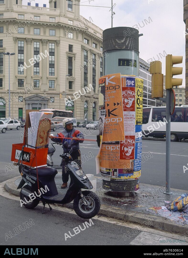 PEGANDO CARTELES EN EL MOBILIARIO URBANO DEL PASEO DE GRACIA.