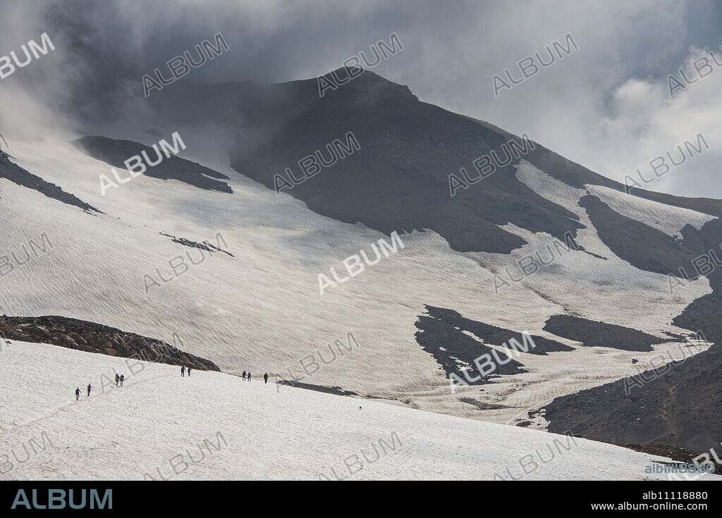 Tourists crossing a snowfield, Mutnovsky volcano, Kamchatka, Russia, Eurasia.