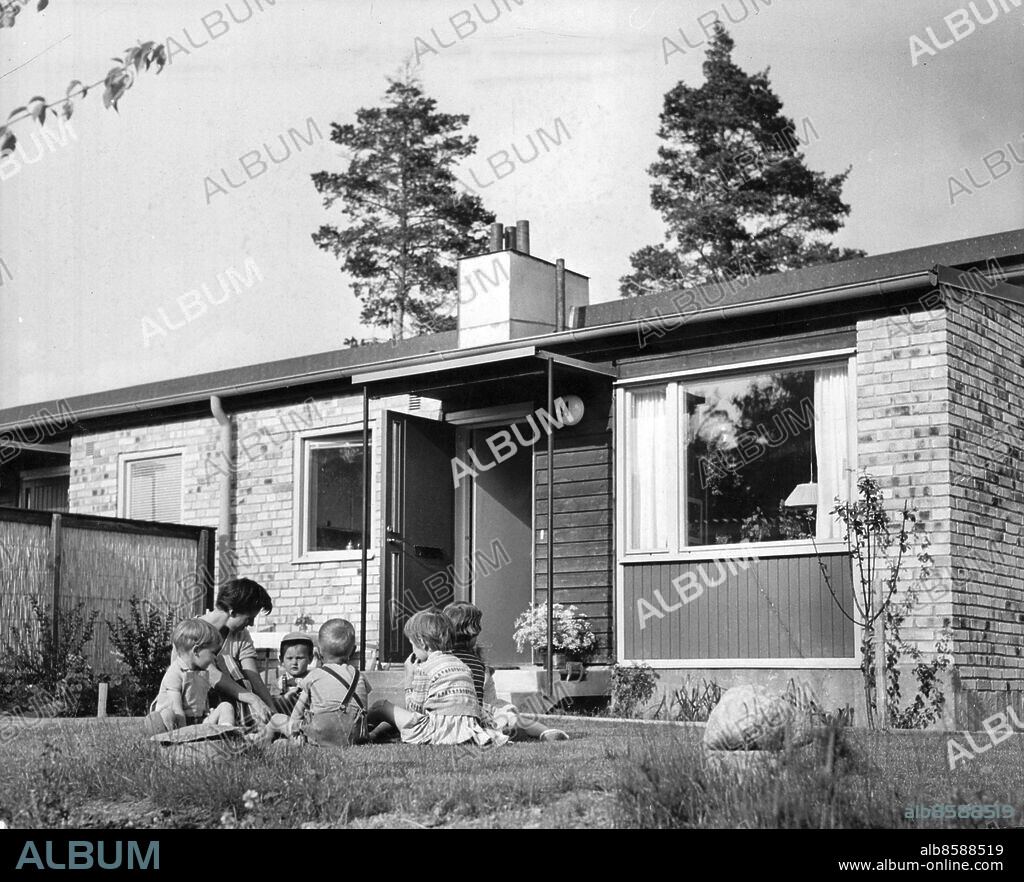 Stockholm 1958-06-25. Radhusliv i Vällingby. Här sitter fru Gun Ridderstolpe med egna och grannarnas barn i gräset framför sitt radhus på Tornedalsgatan.. Foto: Folke Hellberg / DN / TT / Kod: 23. ** SvD OUT **.