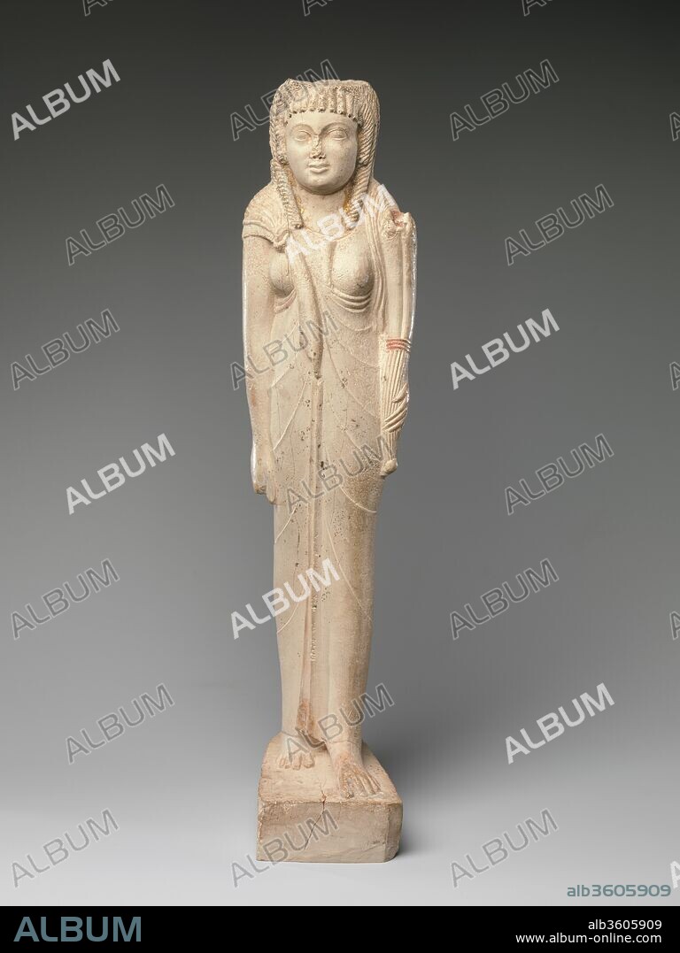 Statuette of Arsinoe II for her Posthumous Cult. Dimensions: H. 38.7 cm (15 1/4 in); W. 9.6 cm (3 3/4 in); D. 13.2 cm (5 3/16 in). Date: ca. 150-100 B.C..
The inscription on the back of this figure refers to Queen Arsinoe II as a goddess, indicating it was made after 270 B.C. when her cult was established at the time of her death in by her brother and husband, Ptolemy II. Gilding indicating divinity once covered her face, and traces still remain at the edges of her neckline. 
While the overall frontal pose and disposition of the limbs in this small statue follows Egyptian traditions, the cornucopia the queen holds is a Greek divine attribute, and her corkscrew are strongly associated with Hellenistic traditions in Egypt. Features of the depiction - the small Cupid's bow mouth and the large rounded eyes - are also elements from Greek style. Stylistic comparisons indicate this statue was created in the second half of the second century B.C.
Arsinoe's deification is part of the phenomenon of ruler cults in the Hellenistic world established to honor leaders, sometimes even while living; statues of the deified ruler might be placed in the temples of other gods. The importance of native goddesses like Isis and Hathor might have encouraged the Ptolemies to establish a prominent queen. Worship of Egyptian pharaonic period queens is rather rare, although there are notable exceptions such as Ahmose-Nefertari.