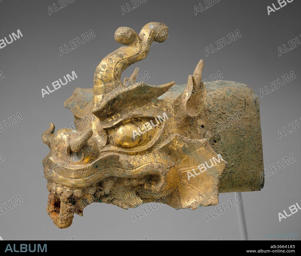 Rafter finial in the shape of a dragon's head and wind chime. Culture: Korea. Dimensions: Finial: L. 15 1/2 in. (39.4 cm); H. 11 3/4 in. (29.8 cm); W. 9 in. (22.9 cm); Chime: H. 15 1/4 in. (38.7 cm); W. 7 1/4 in. (18.4 cm). Date: 10th century.
This finial in the shape of a dragon's head would originally have been attached to a corner rafter of a royal hall or a Buddhist temple building (see, for example, the photograph to the left of a model pagoda that replicates a full-size wood structure from the Goryeo dynasty).
The beast's bulging eyes, flaring nostrils, and elaborate scales convey the fierceness and invincibility of this auspicious creature. The small holes at the sides of the neck were probably used to secure the heavy object to the roof. The bell, which functioned as a wind chime, once had a metal-plate clapper inside. The bell would have been suspended from the loop at the mouth of the dragon by a hook. The decorative panels on the lower halves of both faces of the bell feature a swastika (an ancient symbol associated with the Buddha) within a lotus-flower platform. A nearly identical set of a dragon's head and wind chime, the only other comparable extant example, is in the collection of the Leeum, Samsung Museum of Art in Seoul.
