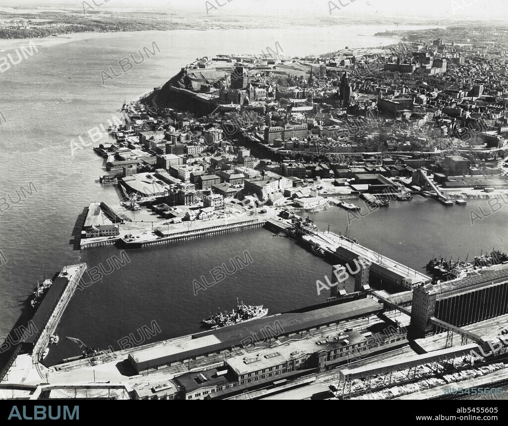 Quebec City:
Located on high ground overlooking the St. Lawrence River, Quebec is one of the oldest and most historic cities in Canada. The above airview was taken looking across the excellent port facilities, toward the towers and spires of the city which surround the historic citadel with the Plains of Abraham and Wolfe Cove in the background. June 18, 1946. (Photo by Photographic Survey Ltd.).