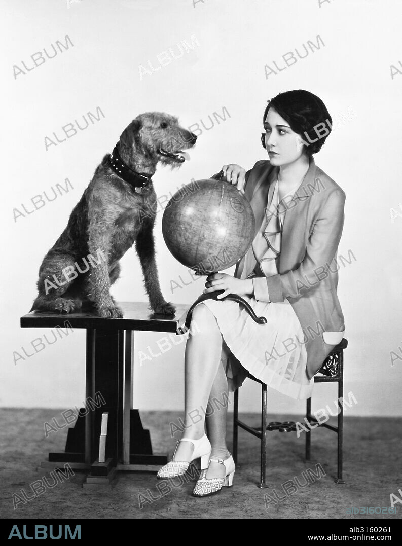 Hollywood, California: c. 1929 Actress Dorothy Sebastian checks out the world globe with Banjo, a dog who has crossed the Atlantic nine times.