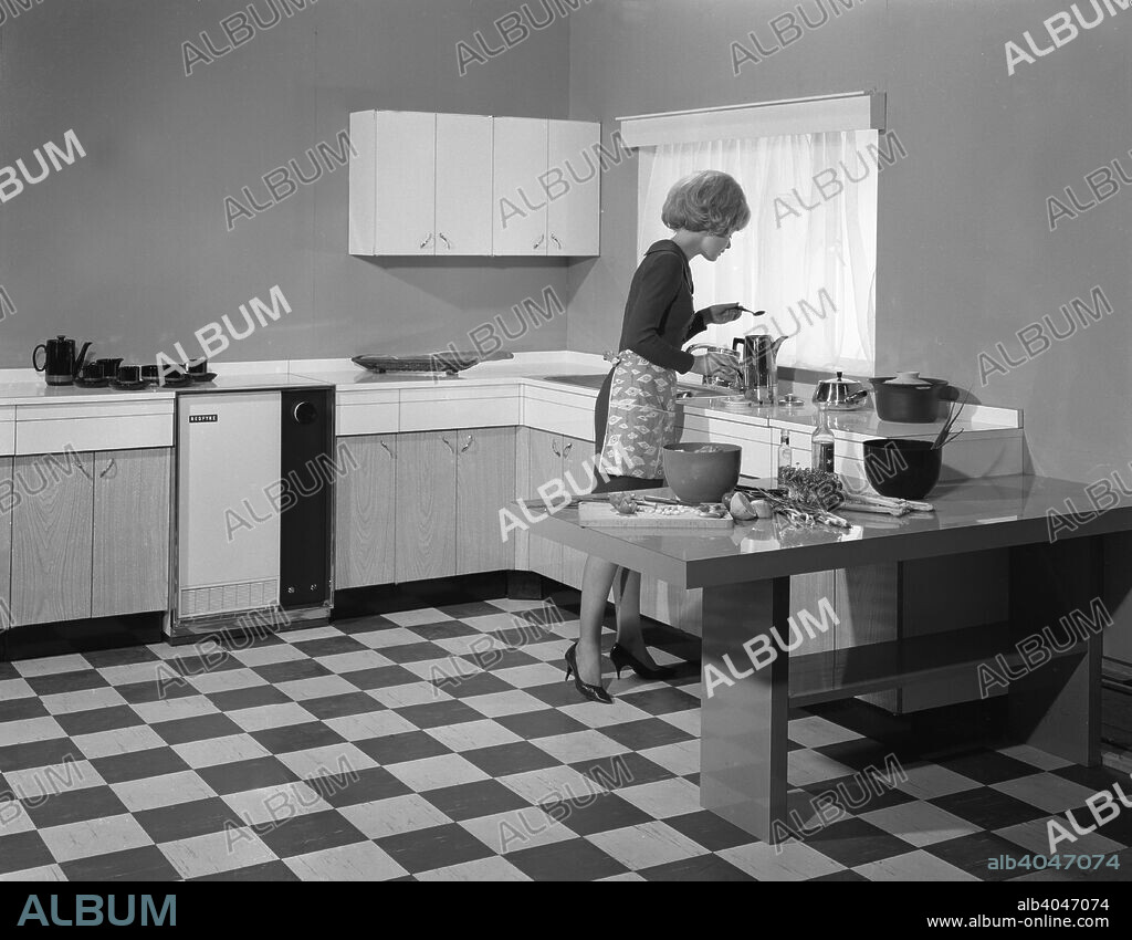 Kitchen scene, Warwick, Warwickshire, 1966. In this advertising image a model is seen preparing a salad in her modern, fitted kitchen with a split level cooker. The 1960s saw the introduction of the 'American' style fitted kitchen which is normal in all homes today.