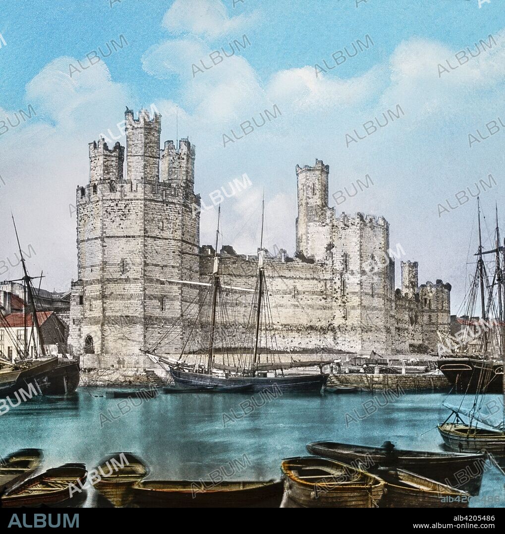 Magic Lantern slide circa 1900 hand coloured. created in 1887. Carnarvon,caenarfon,Castle, from the Ferry.â€”This view is taken from the other side of the River Seoint, and gives one a fair idea of the grandeur of this noble building, which is one of the finest ruins of its kind in the empire. The towers are of admirable proportions, that known as the Eagle Tower being the finest and strongest, and having three turrets above its roof, as seen in the view. From the summit of this tower we get a splendid prospect of surrounding scenery, and also a bird's-eye view of the Castle itself, and a notion of its stability, vastness, and venerability. This is another of the Castles erected by Edward I.