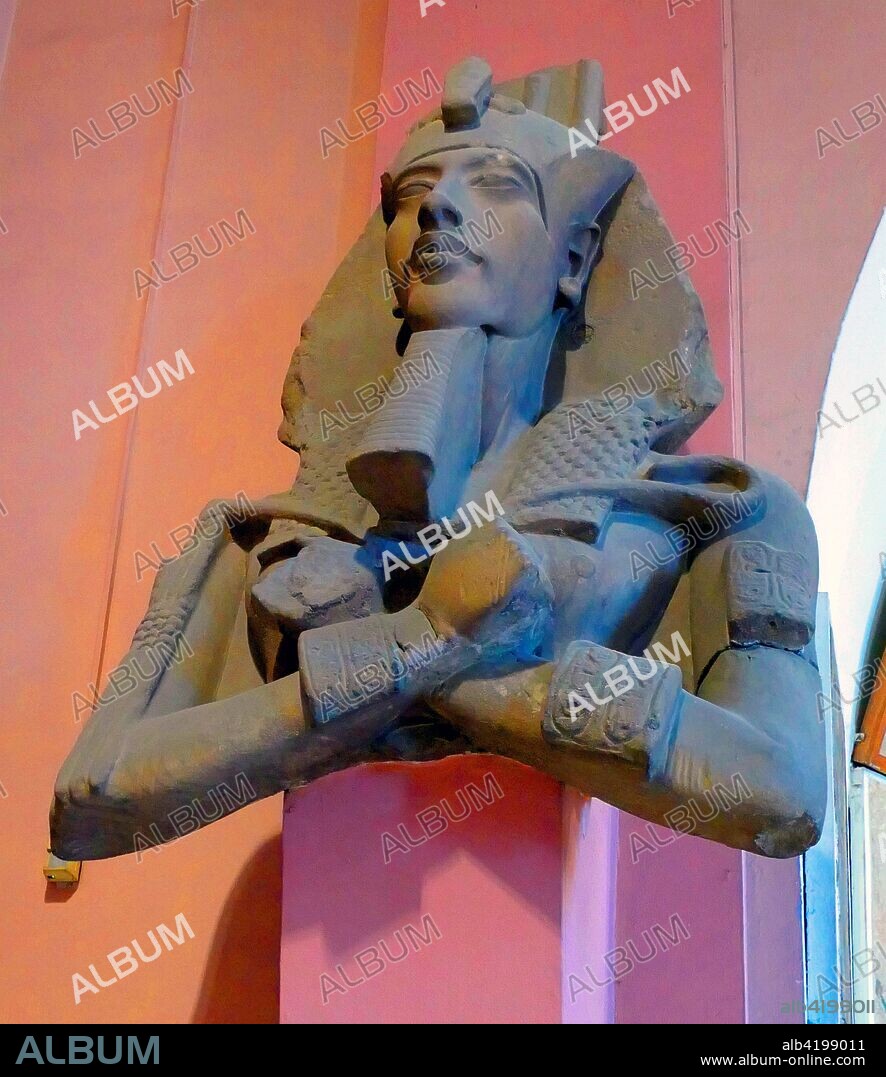 Statue of Akhenaten (Reigned c. 1351-1334 BC). I8th Dynasty. One of a series of colossal statues that once lined a colonnade in the Precinct of the Aten at Karnak. this statue shows Amenhotep IV wearing the nemes headdress topped by the ostrich plumes traditionally wom by Shu. god of the air. The temples in this complex were built early in this king’s reign. and were dismantled soon after his death.