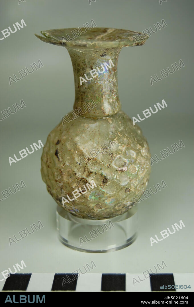 bottle, sprinkler, blown perfume sprinkler or dropper of decolored transparent glass. The bottle has a spherical body with a honeycomb pattern in relief. The piece is blown into a two-piece mold, the malnaad is still vaguely visible. The neck is cylindrical and extends into a flat, disc-shaped lip with a rounded edge. On the transition from shoulder to neck a narrowing is provided on the inside, creating a small round opening for dripping perfumes, bottle, glass, mold blowing, for example. 8.8 cm, diam. 5.2 cm, Greco-Roman Period, Roman imperial age 3rd Century, Egypt.