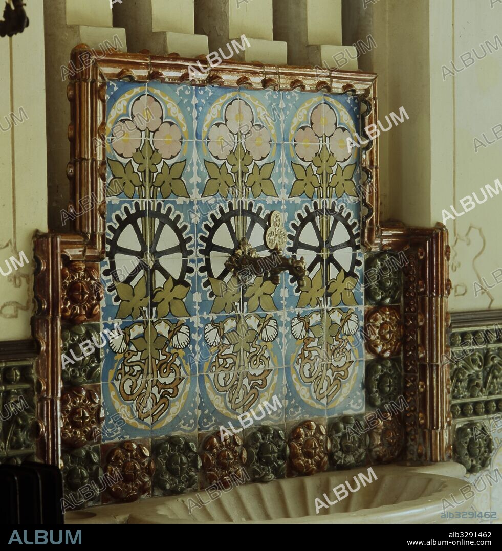 JOSEP PUIG I CADAFALCH. Casa Coll i Regàs, 1898. Lavamanos de piedra con forma de concha. El grifo representa un dragón alado. Decoración con azulejos que representan la planta en flor del  algodón y el lino. Las raíces entrelazadas insinuan la iniciales del propietario (JC) y un tronco con rueda dentada en el medio que evocan al mundo textil. Mataró.