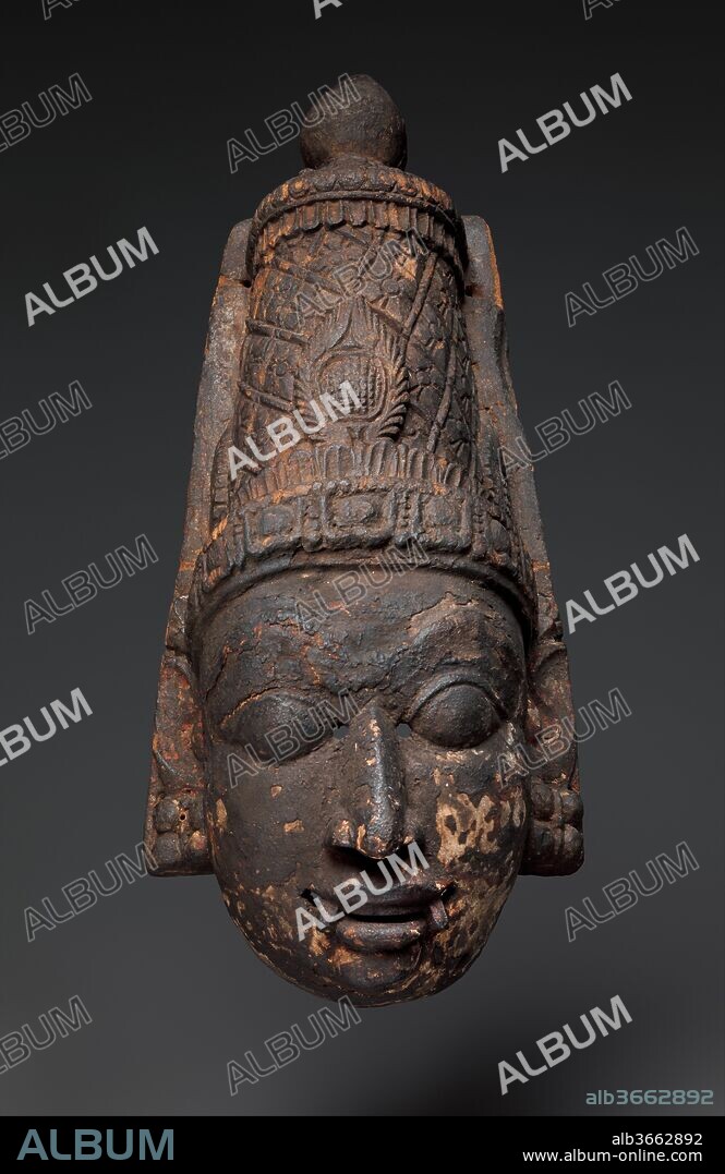 Hiranyakashipu, The Demon-King. Culture: Southern India, Tamil Nadu, probably Thanjavur district. Dimensions: H. 20 in. (50.8 cm); W. 8 1/2 in. (21.6 cm); D. 6 1/4 in. (15.9 cm). Date: ca. 1700-1750.
This version of the crowned demon-king, fanged to denote his demonic nature, is missing its decorative appendages. In some renditions of temple dramas, the characters, with the notable exception of Narasimha, are represented twice on stage. On this work, the fine detailing of the conical crown and jeweled diadem are clearly legible.