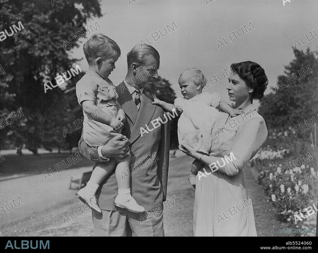 The Happy Family In Their Garden -- Princess Anne, held by her mother Princess Elizabeth, appears to be wanting to go to her father the Duke of Edinburgh who is holding Prince Charles.Pictures just released show H.R.H. Princess Elizabeth and the Duke of Edinburgh with their children Prince Charles and Princess Anne in the garden of the London Home Clarence House. August 09, 1951. (Photo by Barratts Photo-Press-Agency).